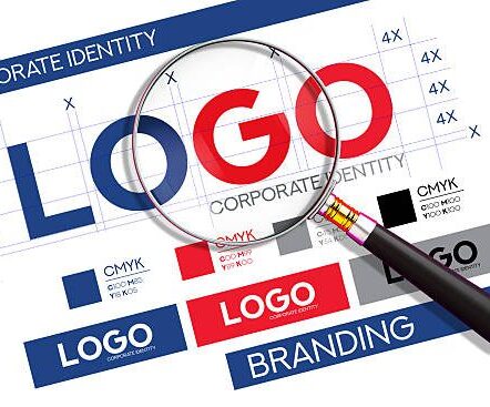 A magnifying glass closely examines a logo on a corporate identity and branding guide, highlighting the meticulous process of brand development. The document includes grid lines for precision, color swatches with CMYK values, and various logo mockups, illustrating the creation of a strong visual identity. This image is perfect for graphic designers, marketing agencies, and businesses to represent concepts like brand strategy, logo creation, quality control, and the importance of a well-defined corporate identity.